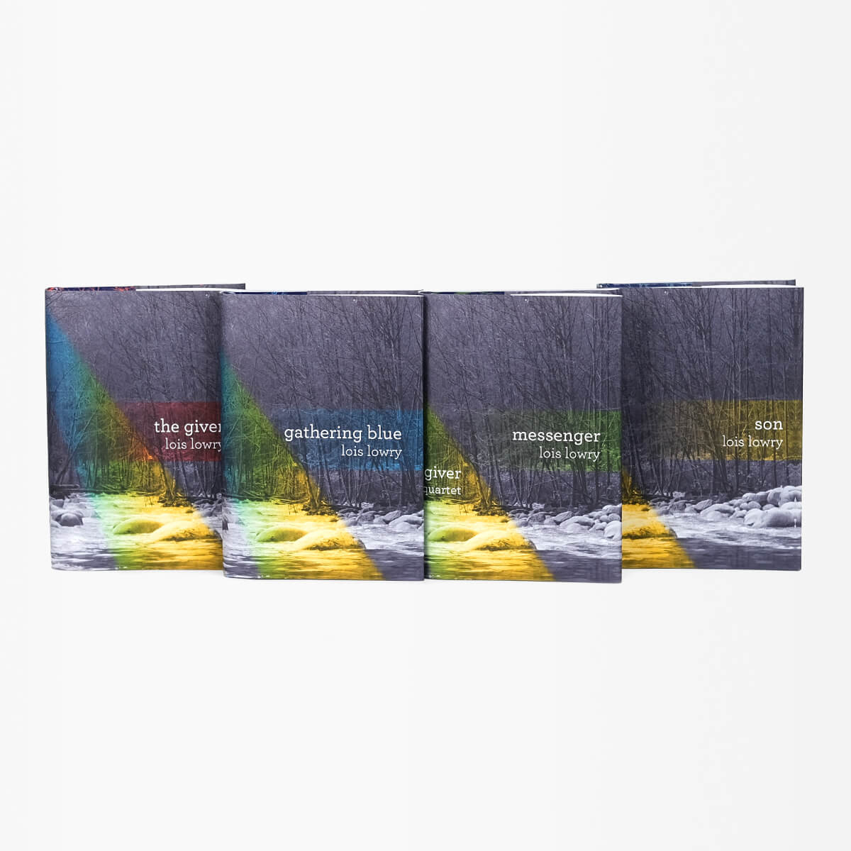 The Giver Quartet cover treatment features book title and author, Lois Lowry, in a simple white serif type against a photo in black and white of a river and woods.