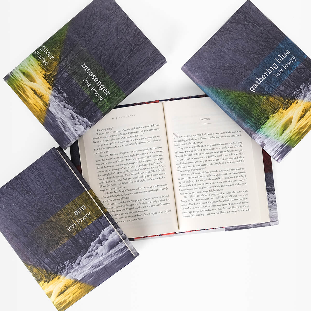 Close up open book  in The Giver Quartet to show print size. Open book is surrounded by other books in the series.