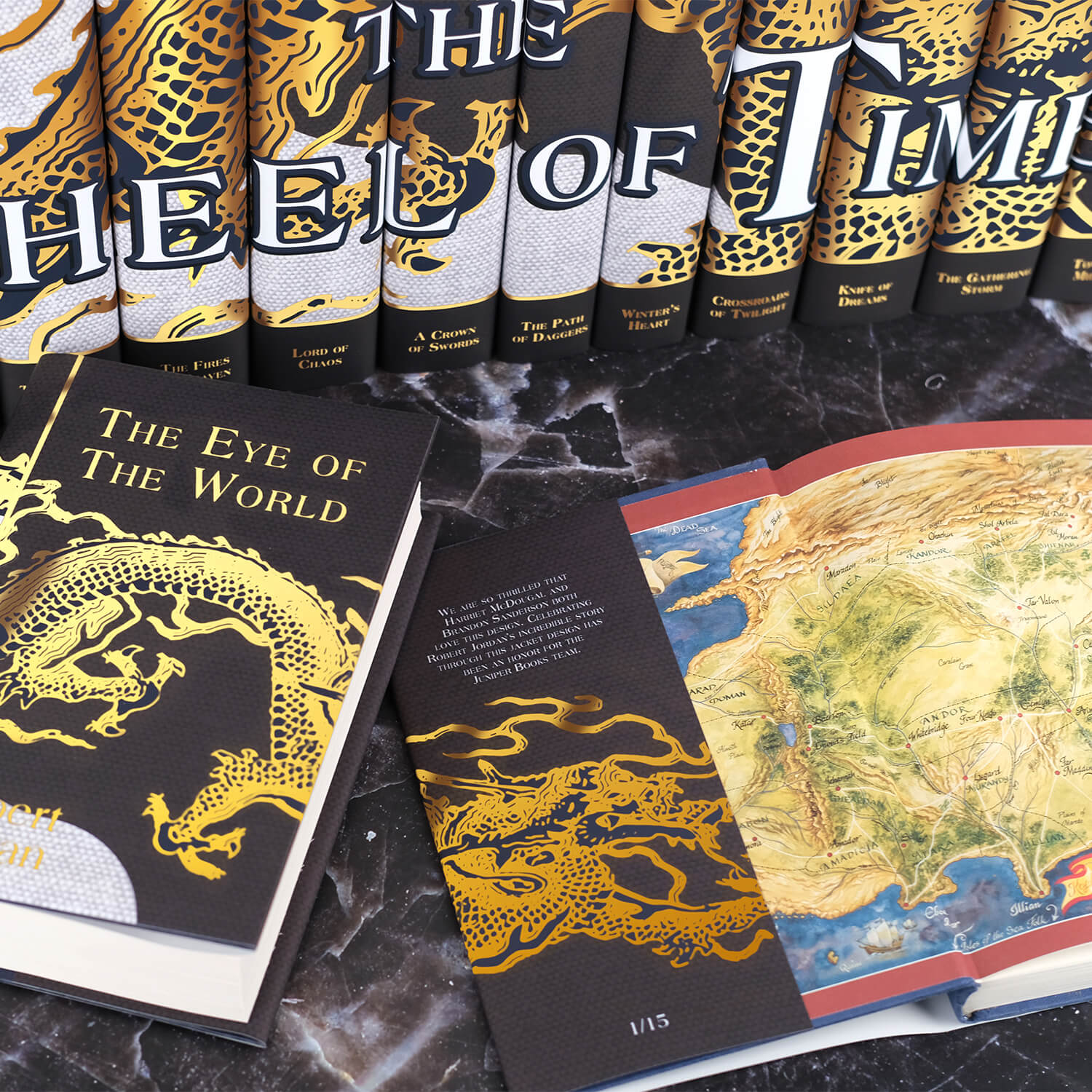Open book view of New Spring set against the other books in the series by Robert Jordan. Open book displays flap text on the inner front flap. The covers feature a gold foil dragon traveling across the front onto the inner flap. Book titles and the author's name on the front cover are in gold foil. All three books sit on a black marble background.