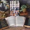 Install photo of the Ernest Hemingway set from Juniper Books. Hemingway set sitting on wood and jute fabric against a stone background surrounded by antique leather books, succulents, and a globe.