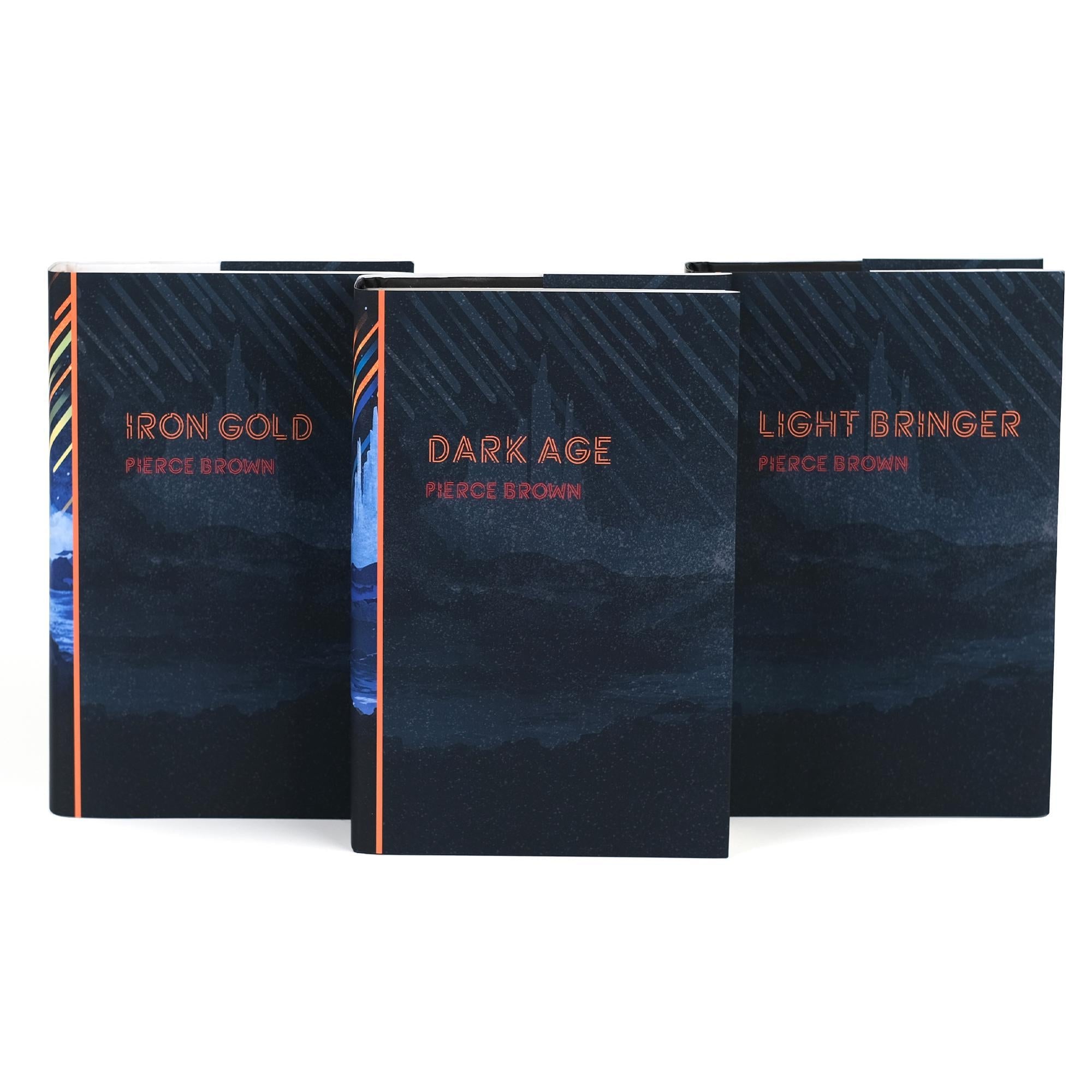 Front view of the covers of Iron Gold, Dark Age, and Light Bringer by Pierce Brown, from the Red Rising series. The covers feature a dark, mountainous landscape with minimalistic design and copper-colored titles and author name. Each book has a similar style with subtle color variations and meteor streaks in the background.