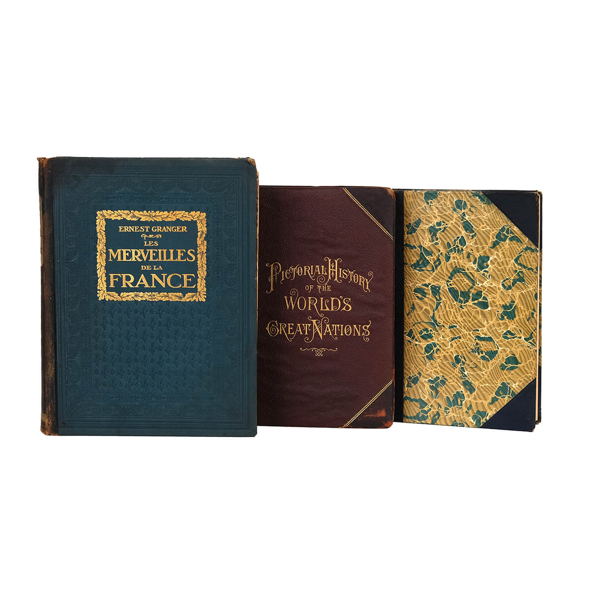 This image displays three antique books with ornate covers and gold detailing.  The first is blue leather, with gold lettering on the cover that reads "Ernest Granger - Les Merveilles de la France." The second is bound in red leather and reads "Pictorial History of the Worlds Great Nations" In decorative typography. The third book features a classic vintage marbled texture in gold and green. These prized collectors items exude an air of timeless sophistication.