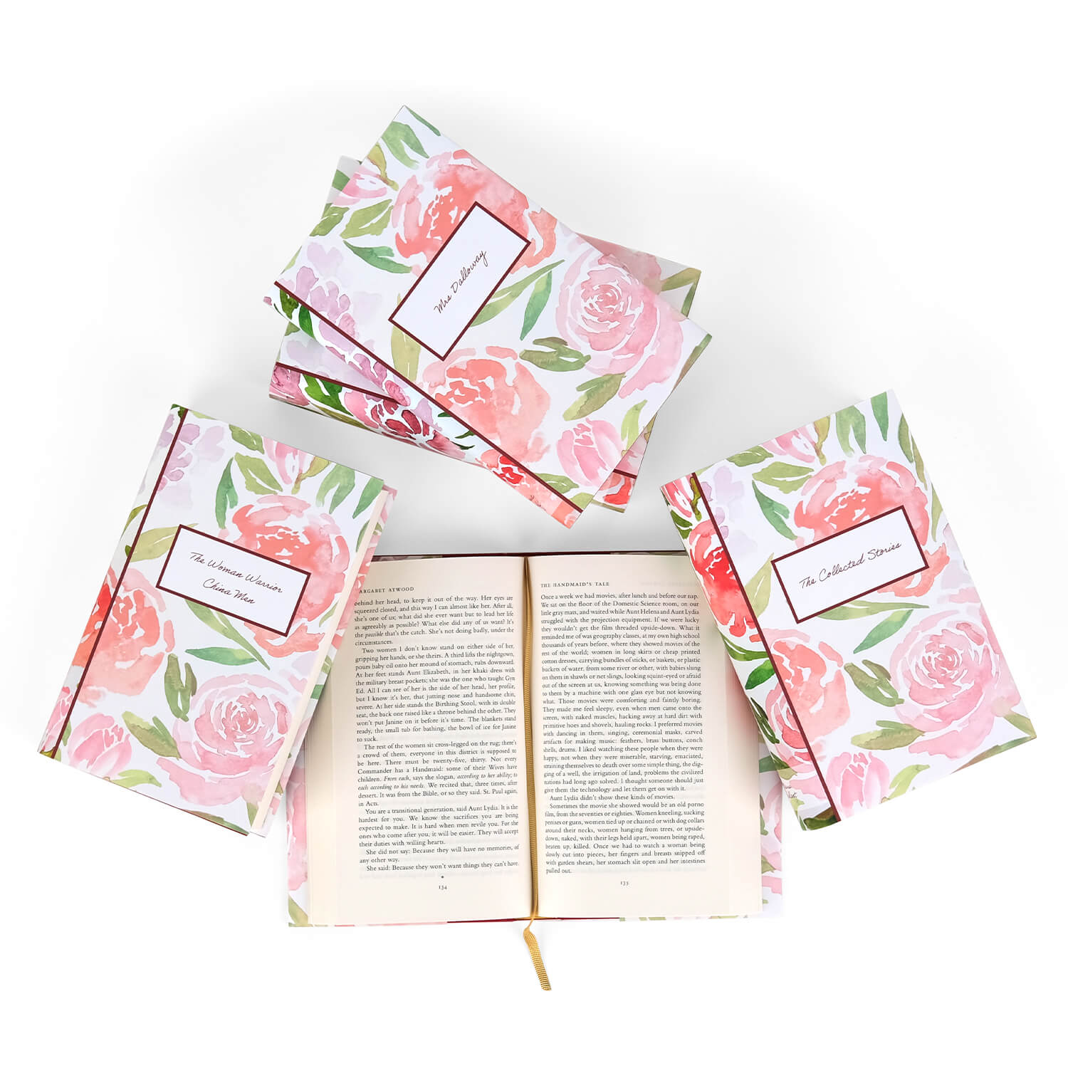 Open book view of The Handmaid's Tale, surrounded by other books in the Influential Women Book Set from Juniper Custom. Open book displays the print size. The covers feature a watercolor rose floral design and the titles on the cover in a white box with burgundy trim.
