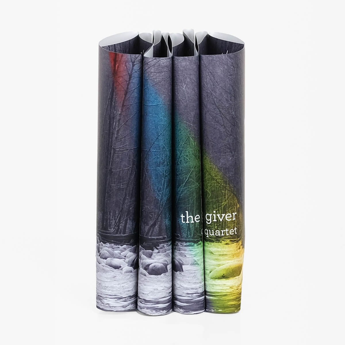 The Giver Quartet custom collectible dust jackets by Juniper Custom. Photo of woods and a river in black and white with a rainbow stretching across spines. The Giver typed across spines in simple white serif font.