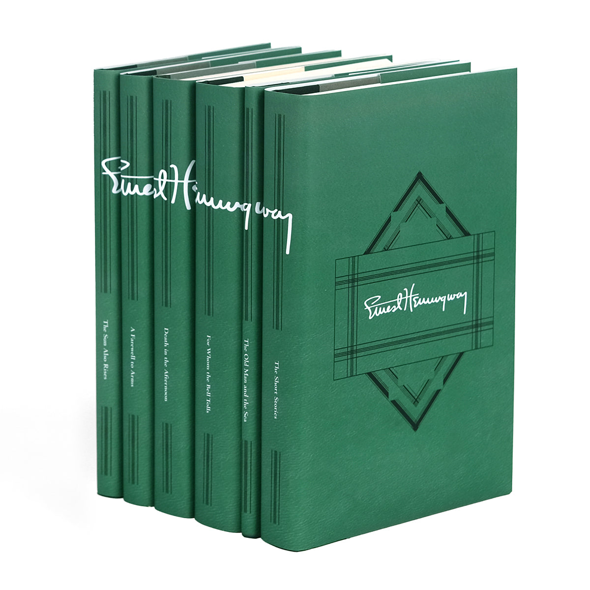 An angled set of six green hardcover books by Ernest Hemingway, with spines aligned to display the author's signature across them in white. Each book spine has a title, from left to right: 'The Sun Also Rises,' 'A Farewell to Arms,' 'Death in the Afternoon,' 'For Whom the Bell Tolls,' 'The Old Man and the Sea,' and 'The Short Stories.' The front cover displays author's signature in white surrounded by a black ornamental design.