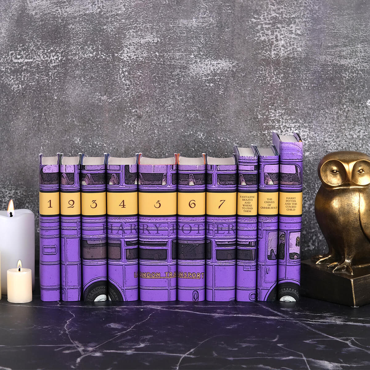 Install shot of Harry Potter Bus Set against a grey stone background surrounded by candles and a gold owl statue.