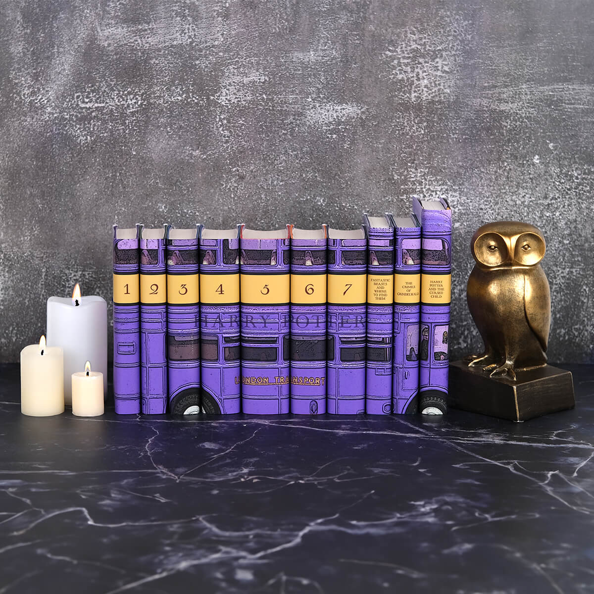 Install shot of Harry Potter Bus Set against a grey stone background surrounded by candles and a gold owl statue.