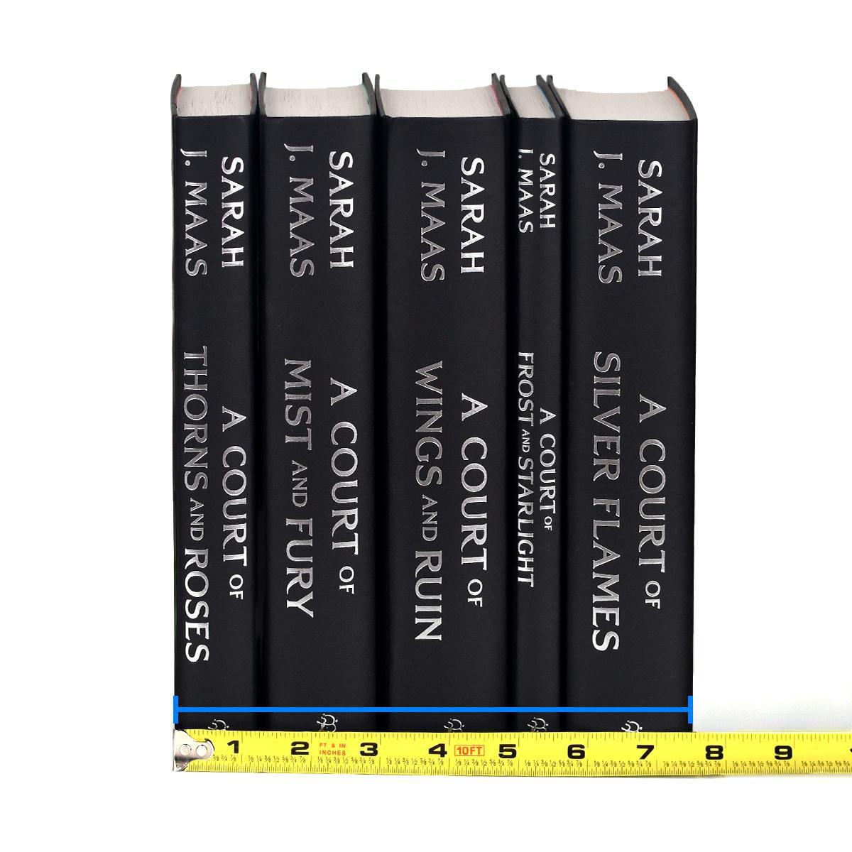 Unjacketed photo of the A Court of Thorns and Roses Series by Sarah J. Maas. Books are black with silver type on the spine detailing book title and author. Tape measure rests against base of spines to show set width.