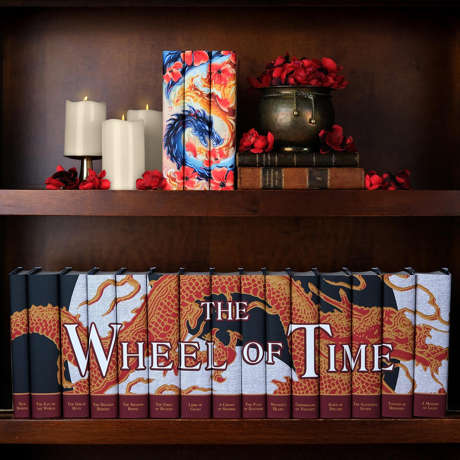 The Poppy War Trilogy R F Kuang Book Set sitting on a dark wood shelf above surrounded by a bronze bowl overflowing with red poppies, antique leather books, white candles, and scattered poppy flowers. The set sits on the shelf above The Wheel of Time Book Set from Juniper Books.