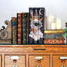 Install shot of The Atlas Series set on a chest of drawers surrounded by antique leather books, ornamental bookend, and candles.