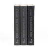 The unjacketed spines of three books by R.F. Kuang from The Poppy War series. The titles, The Poppy War, The Dragon Republic, and The Burning God, are printed in silver lettering on plain black covers with the Harper Voyager logo at the bottom of each spine.