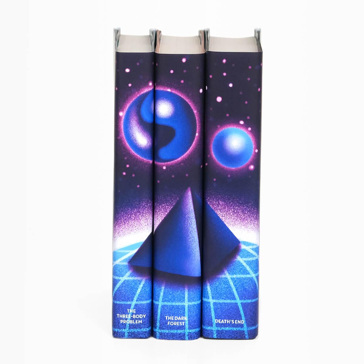 The Three-Body Problem dust jackets features blue and purple shiny orbs floating above a blue pyramid. Book title names typed across bottom of book spines in white serif type.