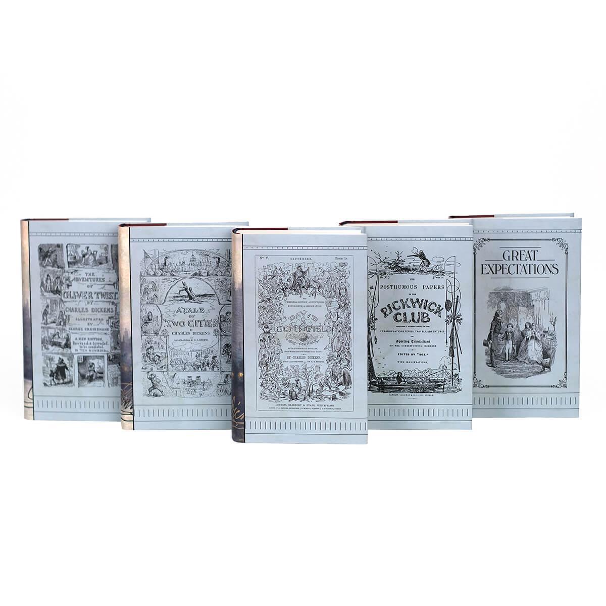 All five books from the Juniper Book Charles Dickens set lined up with illustrated covers facing camera. Each dust jacket cover features a illustration from Dickens books on a light blue background